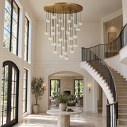 Brass and crystal multi-drop chandelier hanging in a foyer with staircase